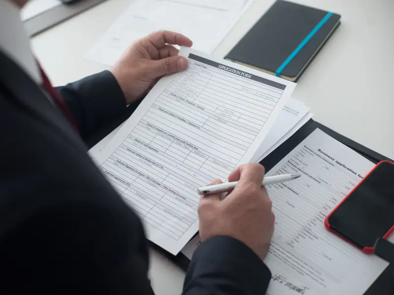 A businessman reviewing a printed application form — visas and residence permits
