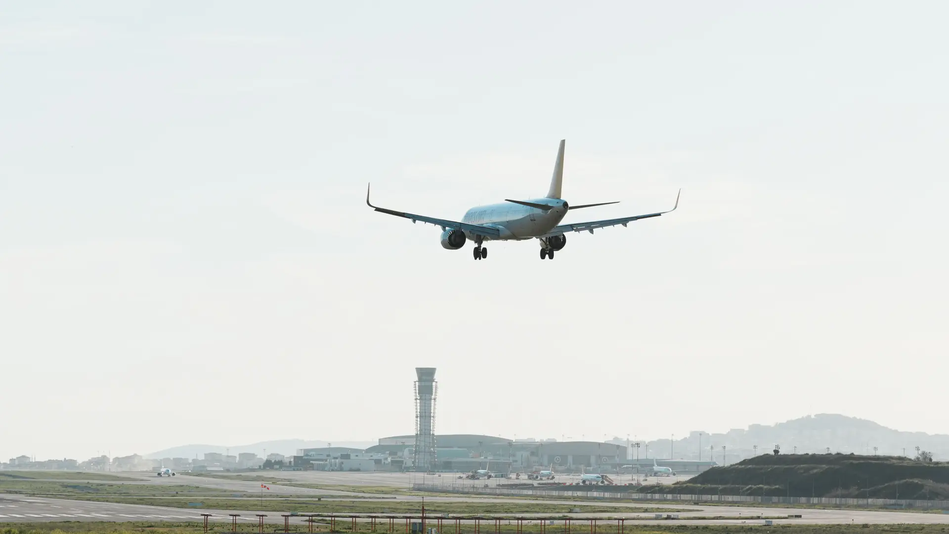 客机放下起落架,在机场跑道上空进行最后进近